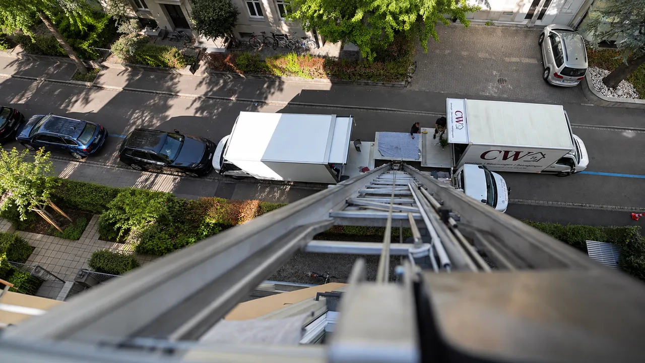 Professioneller Umzug mit Möbellift aus der Vogelperspektive. Mitarbeiter der Firma CW Umzüge & Räumungen transportieren Möbel über einen Außenlift zu den bereitstehenden Umzugsfahrzeugen.